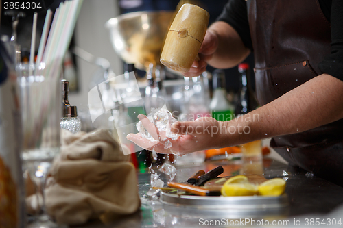 Image of Bartender pours alcoholic drink into small glasses with flames