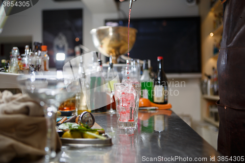 Image of Bartender coocks cocktail behind a bar counter