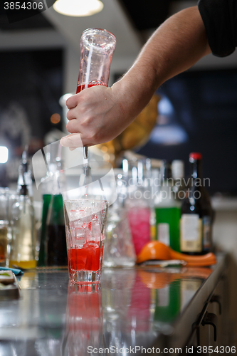 Image of Bartender coocks cocktail behind a bar counter