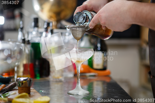 Image of Bartender coocks cocktail behind a bar counter