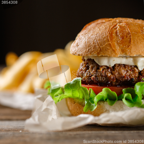 Image of Homemade burger with french fries on wooden table