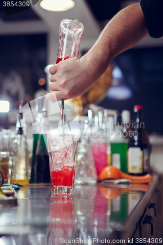 Image of Bartender coocks cocktail behind a bar counter