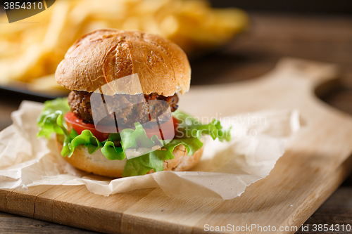 Image of Homemade burger with french fries on wooden table