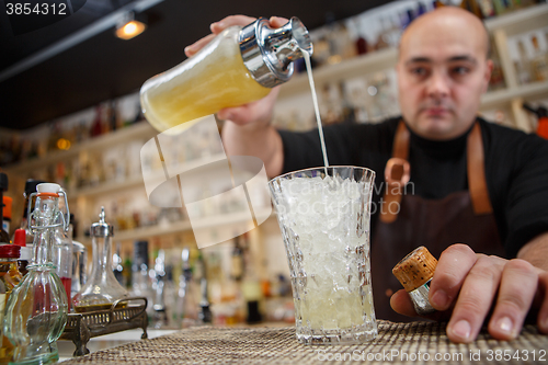 Image of Bartender pouring cocktail into glass at the bar