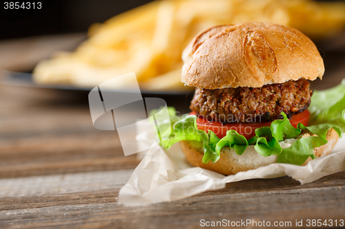 Image of Homemade burger with french fries on wooden table