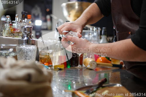 Image of Bartender pours alcoholic drink into small glasses with flames