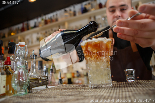 Image of Bartender pouring cocktail into glass at the bar