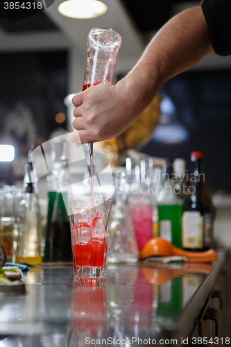 Image of Bartender coocks cocktail behind a bar counter