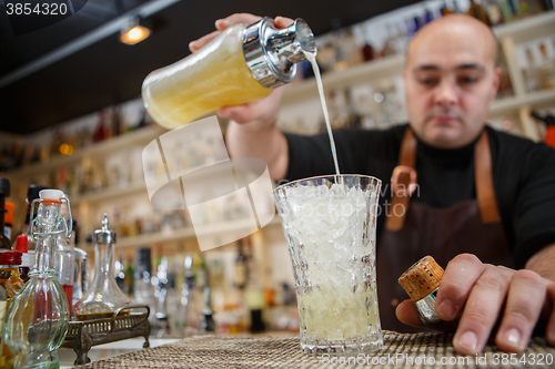 Image of Bartender pouring cocktail into glass at the bar