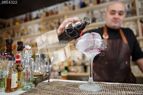 Image of Bartender is pouring wine in the glass with giant ice, wide-angle image.