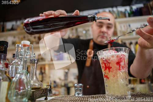 Image of Bartender pouring cocktail into glass at the bar