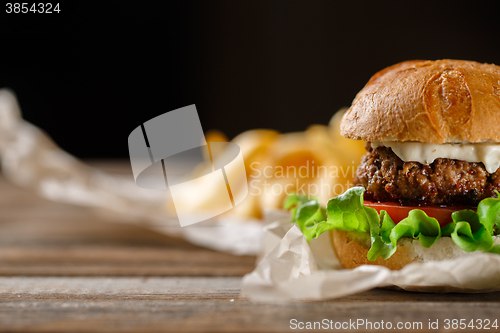 Image of Homemade burger with french fries on wooden table