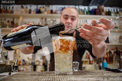 Image of Bartender pouring cocktail into glass at the bar