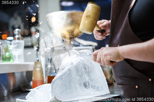 Image of Bartender mannually crushed ice with wooden hammer and metal knife.