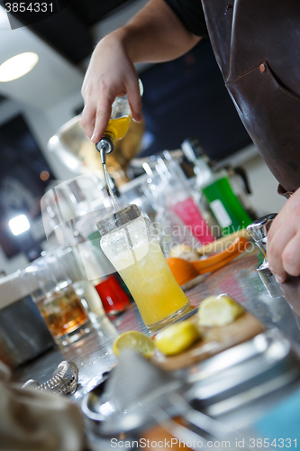 Image of Bartender is straining cocktail in a glass