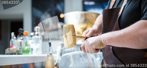 Image of Bartender mannually crushed ice with wooden hammer and metal knife.