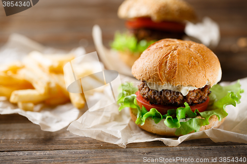 Image of Homemade tasty burger and french fries on wooden table