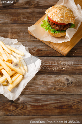 Image of Homemade hamburgers and french fries on wooden table