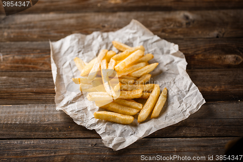 Image of French fries on wooden table.