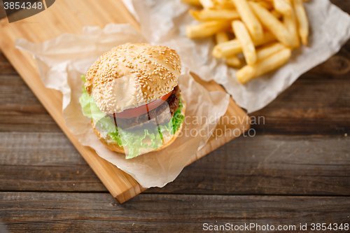 Image of Homemade hamburgers and french fries on wooden table