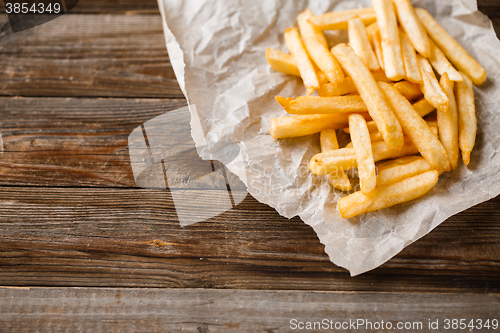 Image of French fries on wooden table.