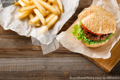 Image of Homemade hamburgers and french fries on wooden table