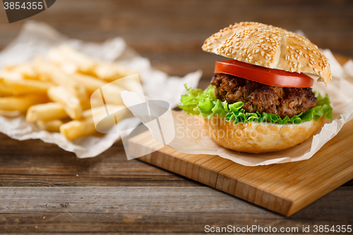 Image of Homemade hamburgers and french fries on wooden table