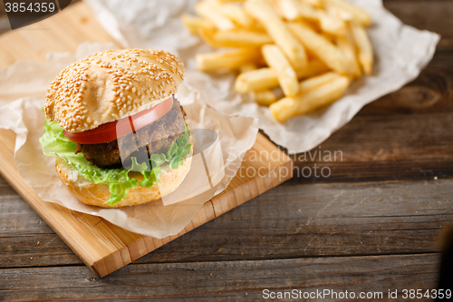 Image of Homemade hamburgers and french fries on wooden table