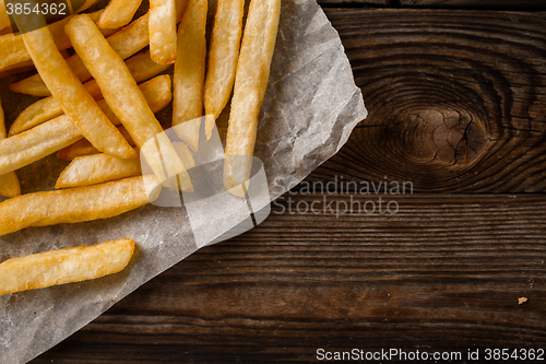 Image of French fries on wooden table.