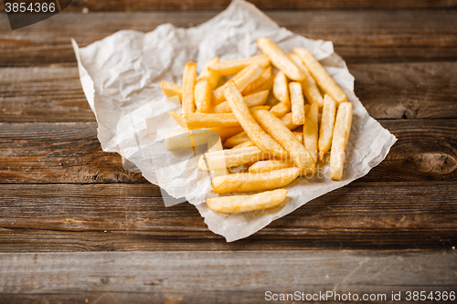 Image of French fries on wooden table.