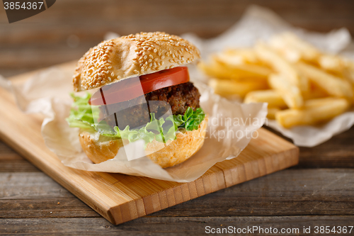 Image of Homemade hamburgers and french fries on wooden table