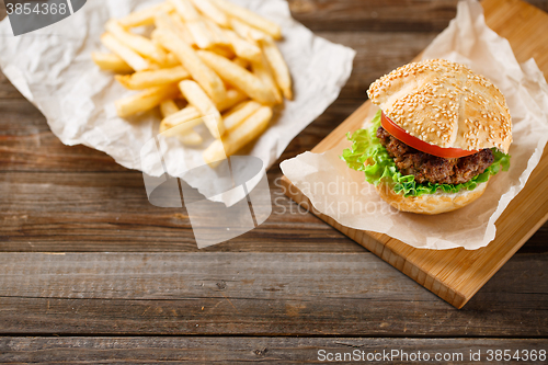 Image of Homemade hamburgers and french fries on wooden table