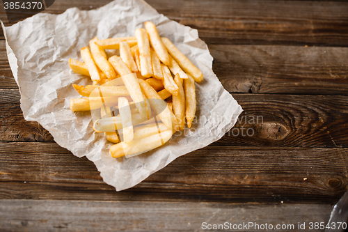 Image of French fries on wooden table.