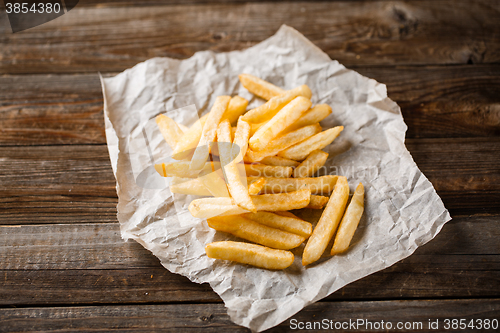 Image of French fries on wooden table.