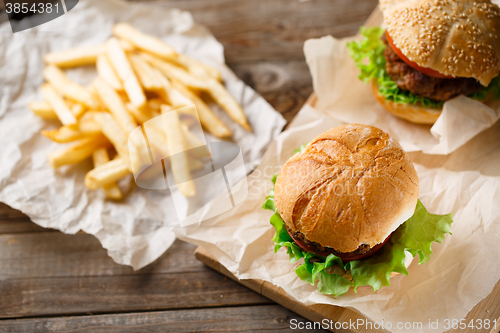 Image of Homemade tasty burger and french fries on wooden table