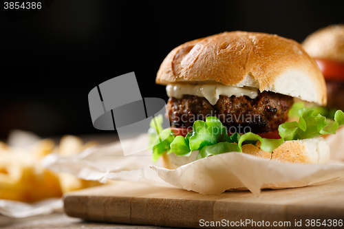 Image of Homemade tasty burger and french fries on wooden table