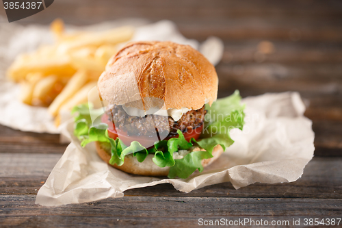 Image of Homemade burger with french fries on wooden table