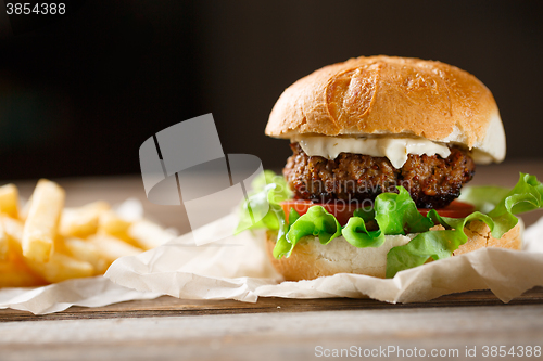 Image of homemade burger and french fries on a wooden plate