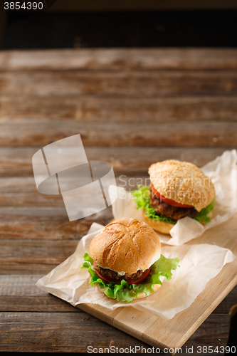 Image of Homemade hamburgers and french fries on wooden table