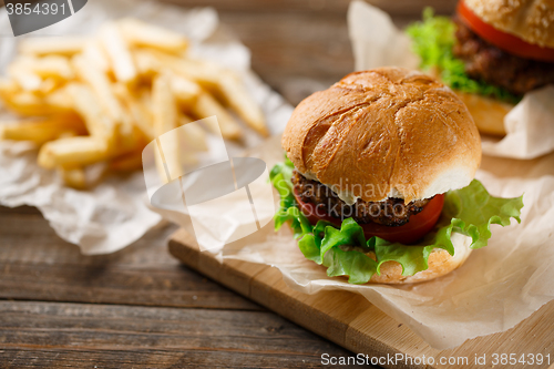 Image of Homemade hamburgers and french fries on wooden table