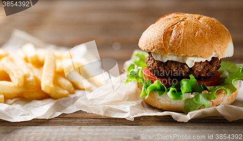 Image of homemade burger and french fries on a wooden plate