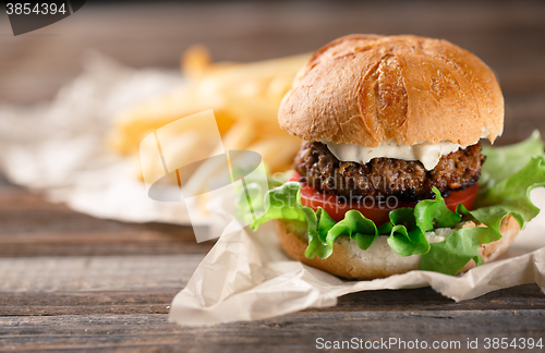 Image of Homemade burger with french fries on wooden table