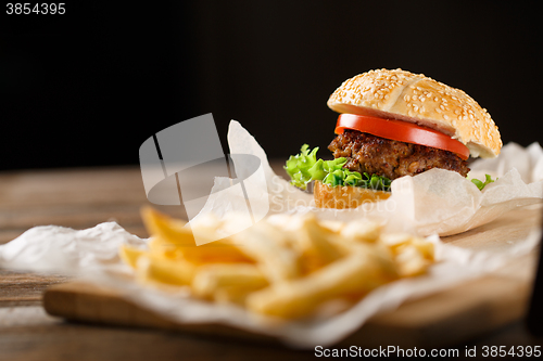 Image of Homemade hamburgers and french fries on wooden table