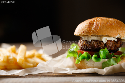 Image of homemade burger and french fries on a wooden plate