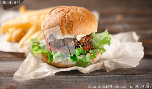 Image of Homemade burger with french fries on wooden table