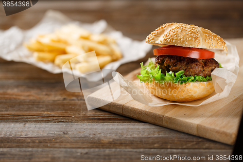 Image of Homemade hamburgers and french fries on wooden table