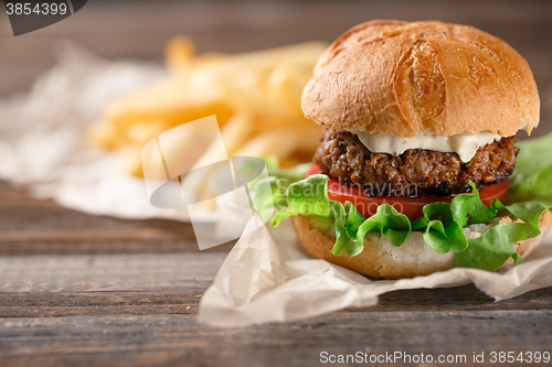 Image of Homemade burger with french fries on wooden table