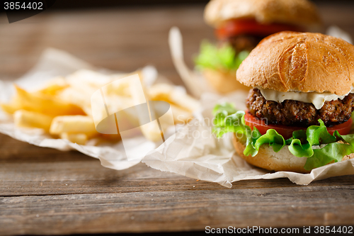 Image of Homemade tasty burger and french fries on wooden table