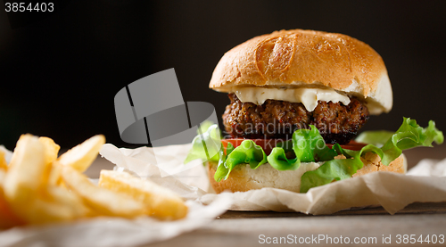 Image of homemade burger and french fries on a wooden plate