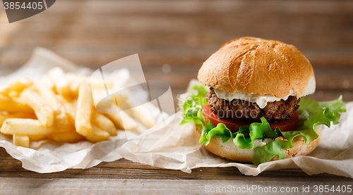 Image of homemade burger and french fries on a wooden plate